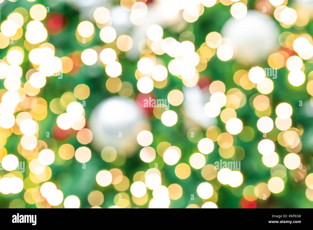 Sfocato rosso, verde e oro bokeh sullo sfondo di un albero di Natale. Sfondo di natale. Natale e Felice Anno Nuovo sfondo per le vacanze. Bellissimo bokeh bac Foto Stock