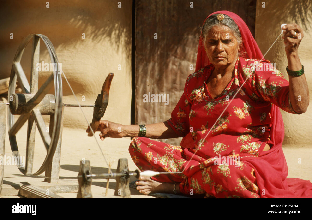 Donna tessitura stoffa con ruota di filatura, Rajasthan, India Foto Stock
