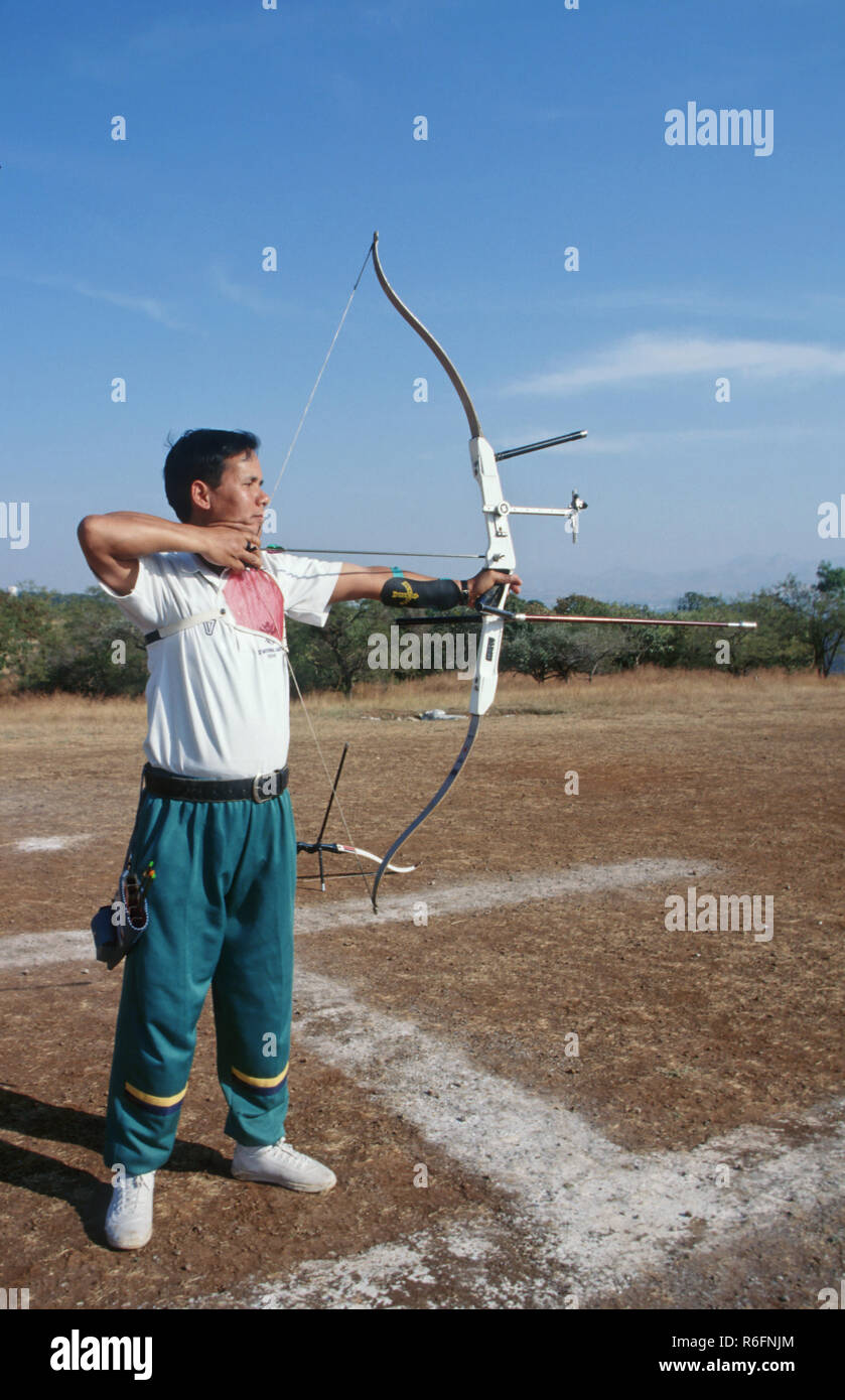 Professional archer con re-prua curva di freccia e bersaglio Foto Stock