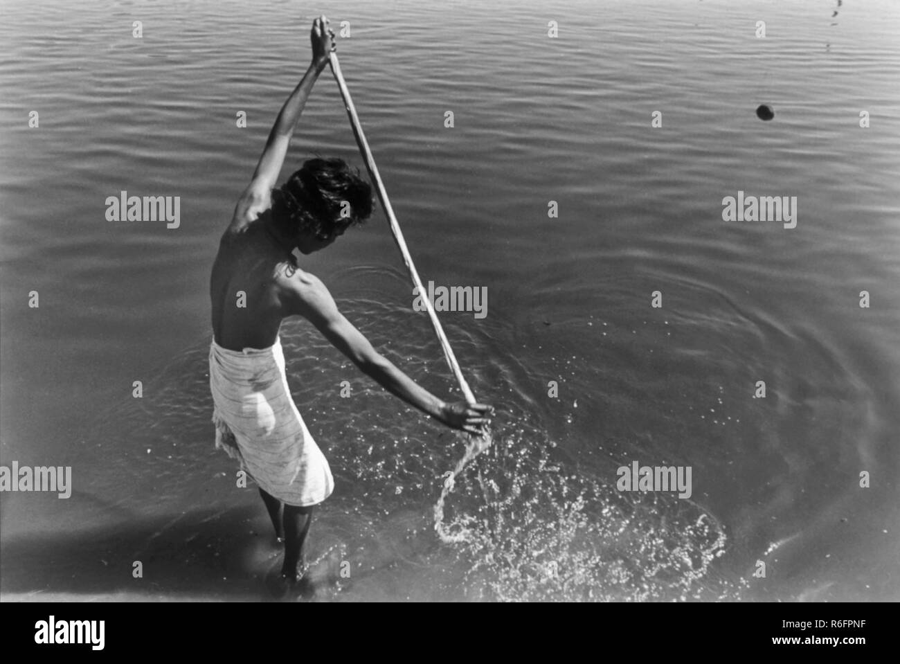 Uomo lavaggio abiti in fiume, India, vecchia annata 1900s foto Foto Stock