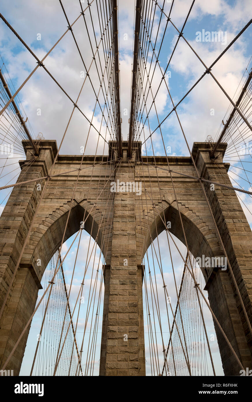 Scenic vista astratta di cavi in acciaio e la tessitura dei mattoni dell'iconico arcata in pietra torre del ponte di Brooklyn in morbido cielo blu al tramonto Foto Stock