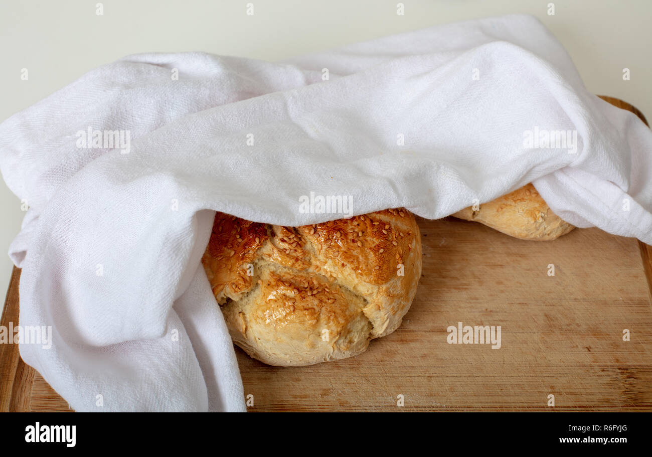 Pane appena sfornato il pane fatto in casa con tessuto bianco sul tagliere di legno ad alto angolo di visione con spazio di copia Foto Stock