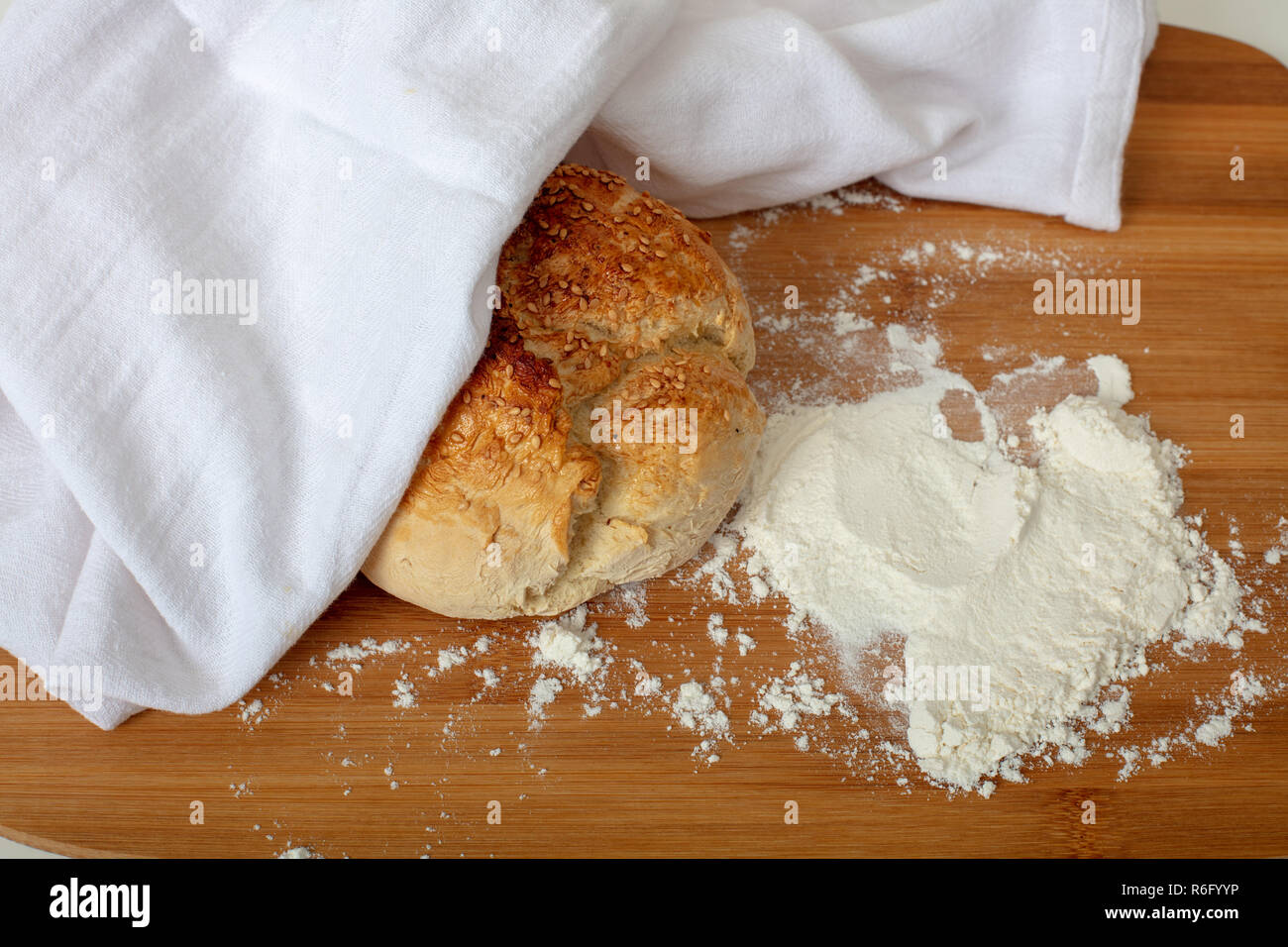 Pane appena sfornato il pane fatto in casa con farina bianca sul tagliere di legno ad alto angolo di visione con spazio di copia Foto Stock