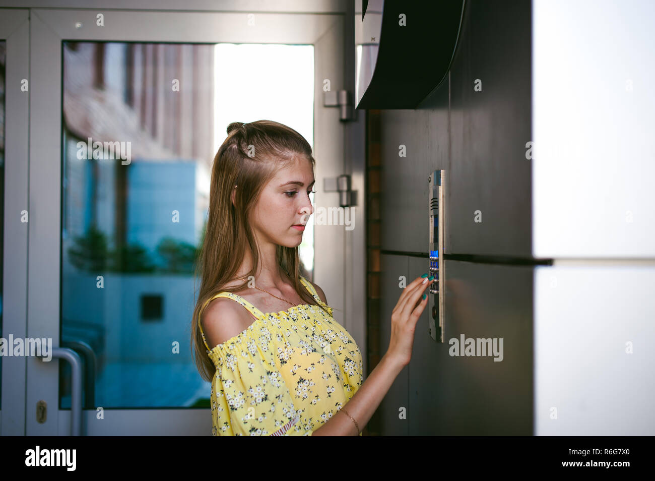 La donna compone un codice appartamento su un sistema elettronico di pannello doorphone Foto Stock