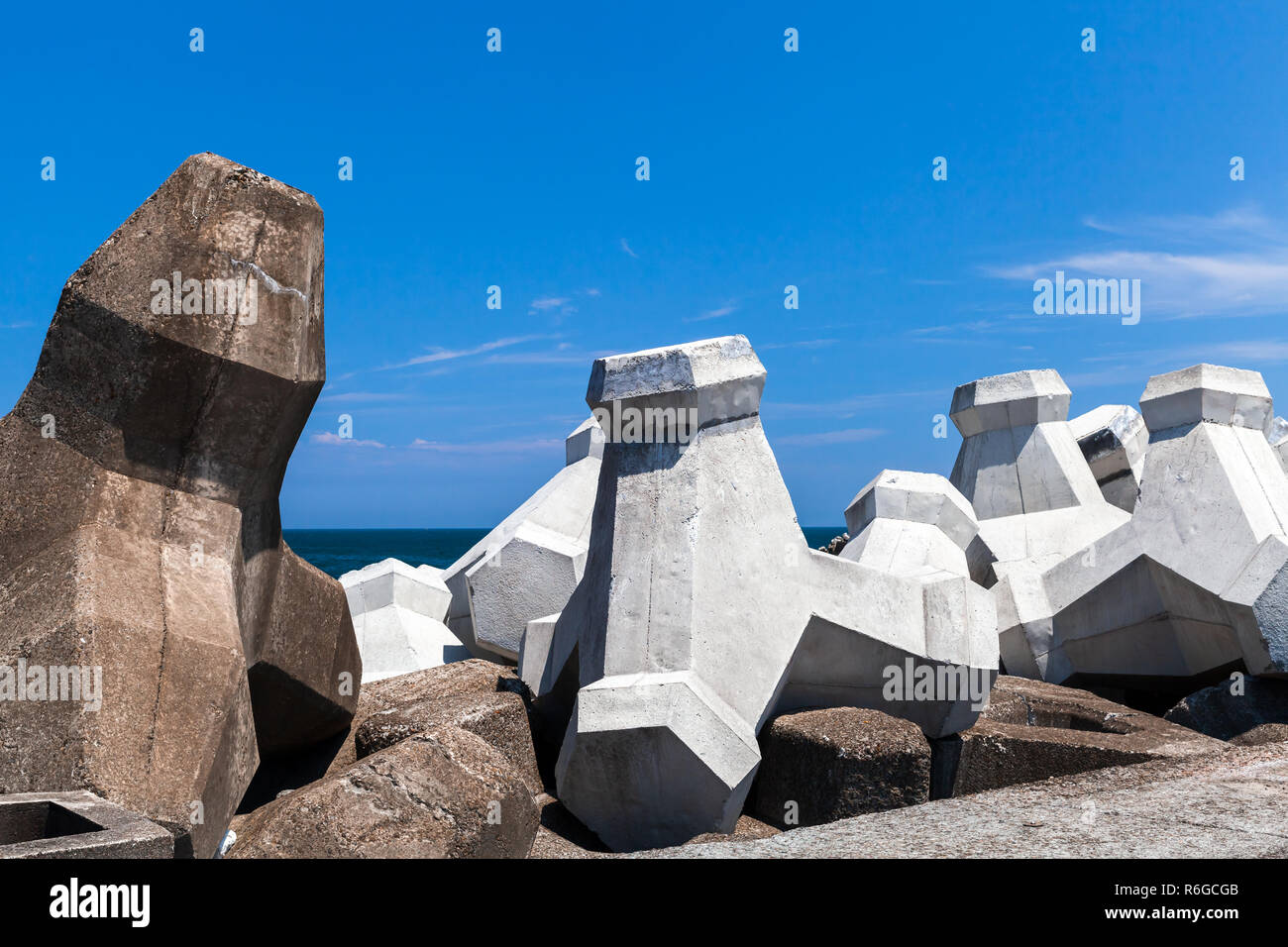 Calcestruzzo ruvido blocchi frangiflutti sono sotto il cielo nuvoloso. Background Industriale foto Foto Stock