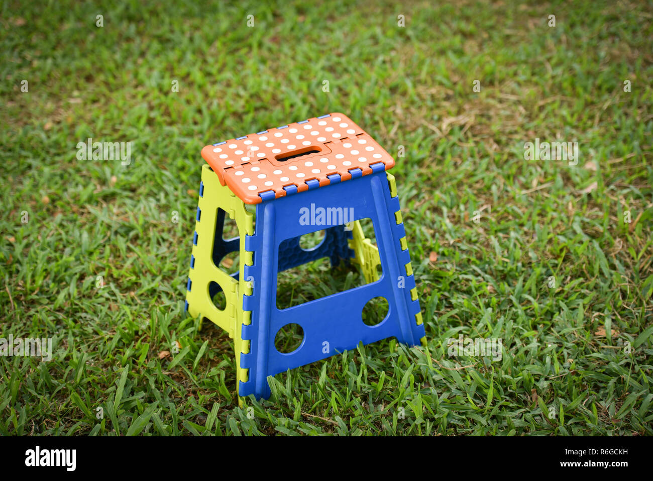 Colorful chairs plastic / folding chair stand on green field in outdoors - camping chair on green grass in the park Foto Stock