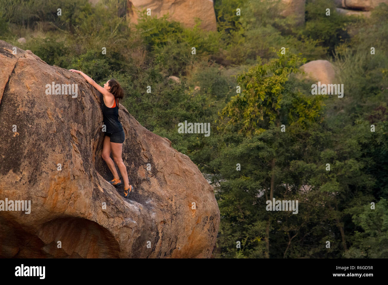 Una femmina di scalatore pratiche la sua arrampicata boulder competenze, Hampi, India. Foto Stock