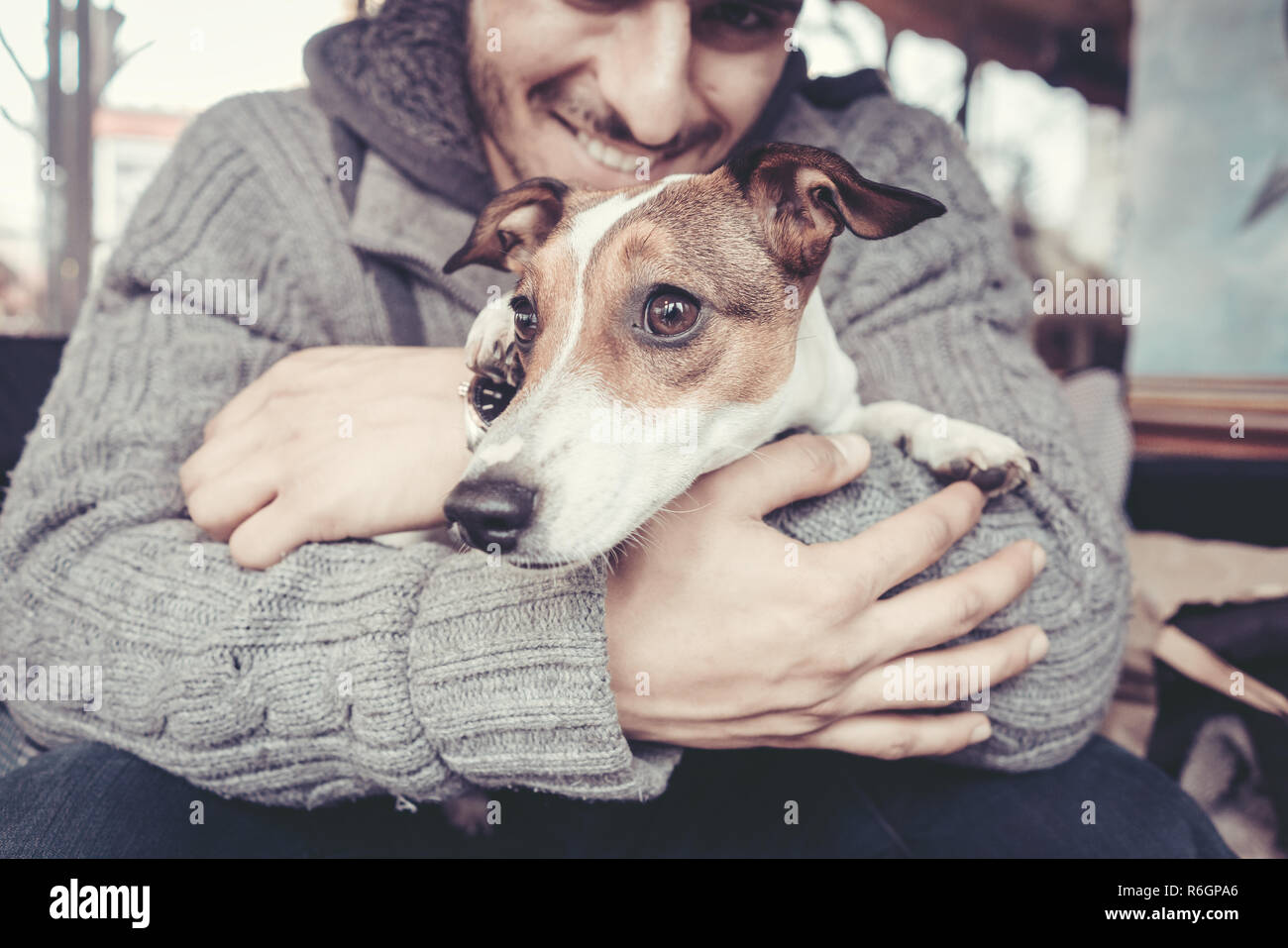 Cuddling l uomo con il suo cane in inverno Foto Stock