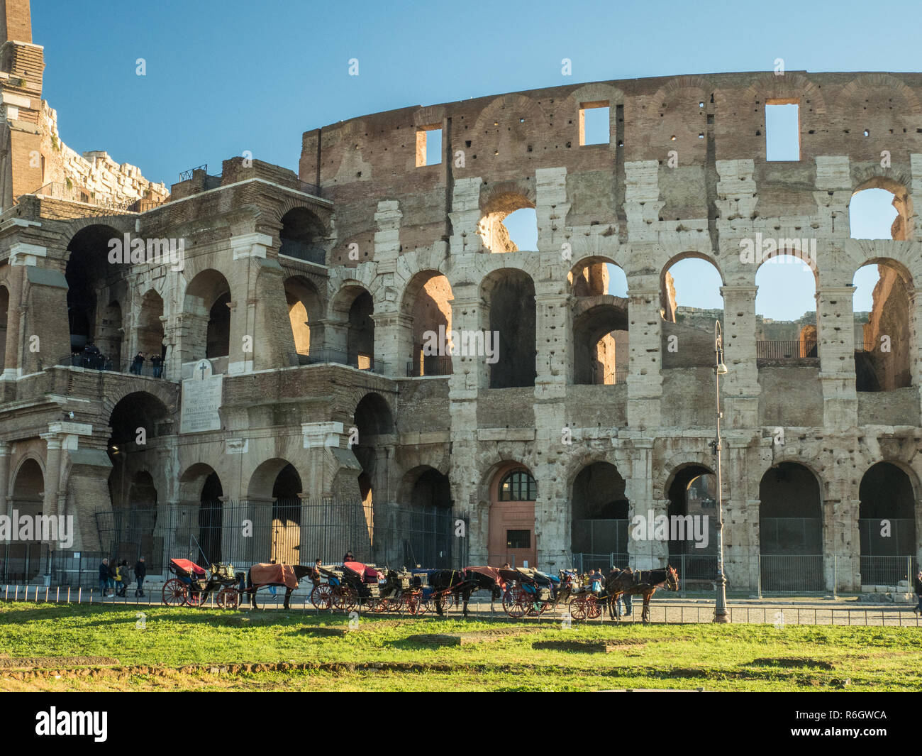 Il Colosseo a Roma, Lazio, Italia. Cavalli con carrozze attendono di portare i turisti in un tour della città. Foto Stock