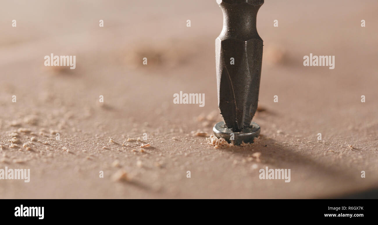 Artigiano aziona la vite nella tavola di legno Foto Stock