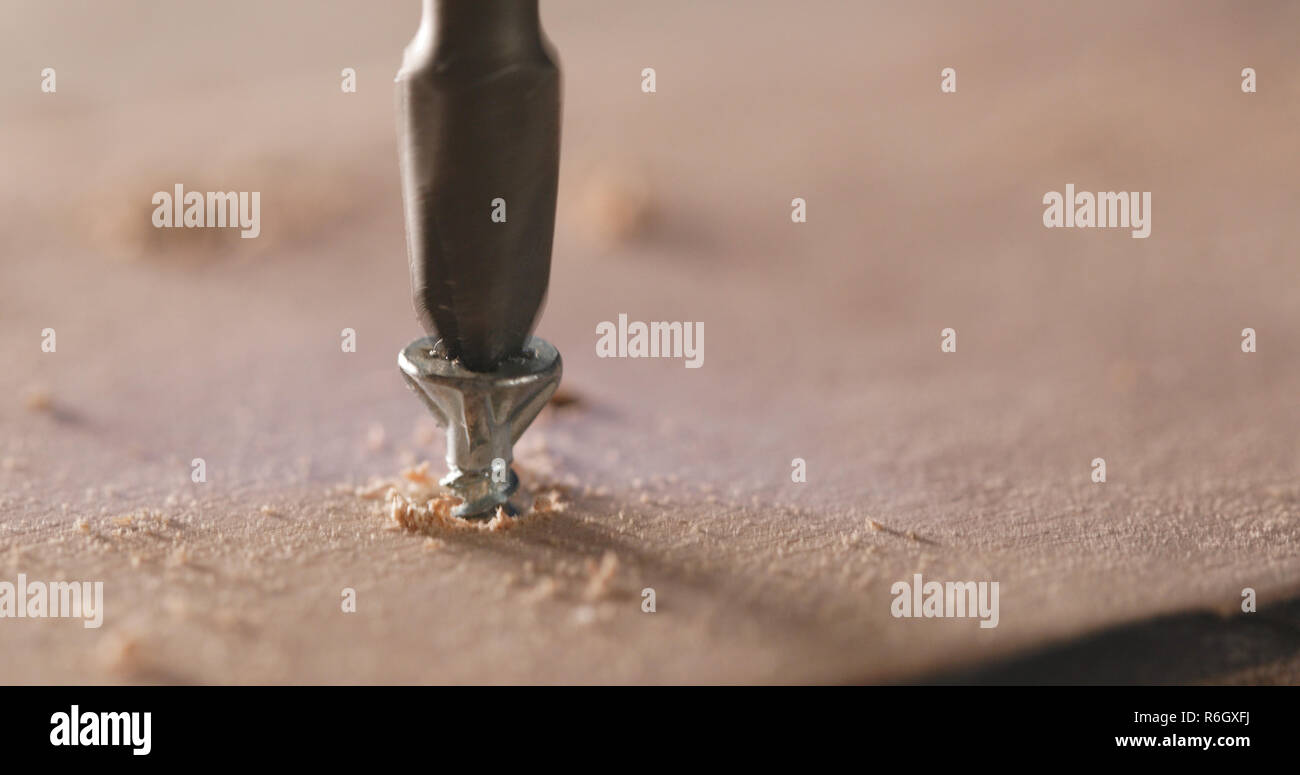 Artigiano aziona la vite nella tavola di legno Foto Stock