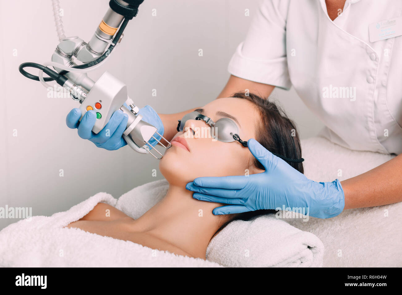 Donna che indossa gli occhiali di protezione, getting laser trattamento facciale. La pelle del viso ringiovanimento Foto Stock