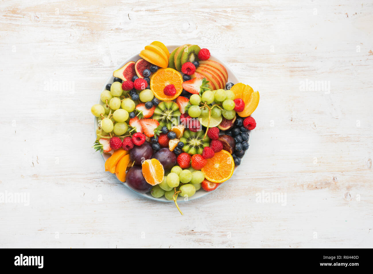 Una sana frutta, fragole lamponi arance Prugne Mele Kiwi uve mirtilli sul bianco tavolo in legno, vista dall'alto Foto Stock