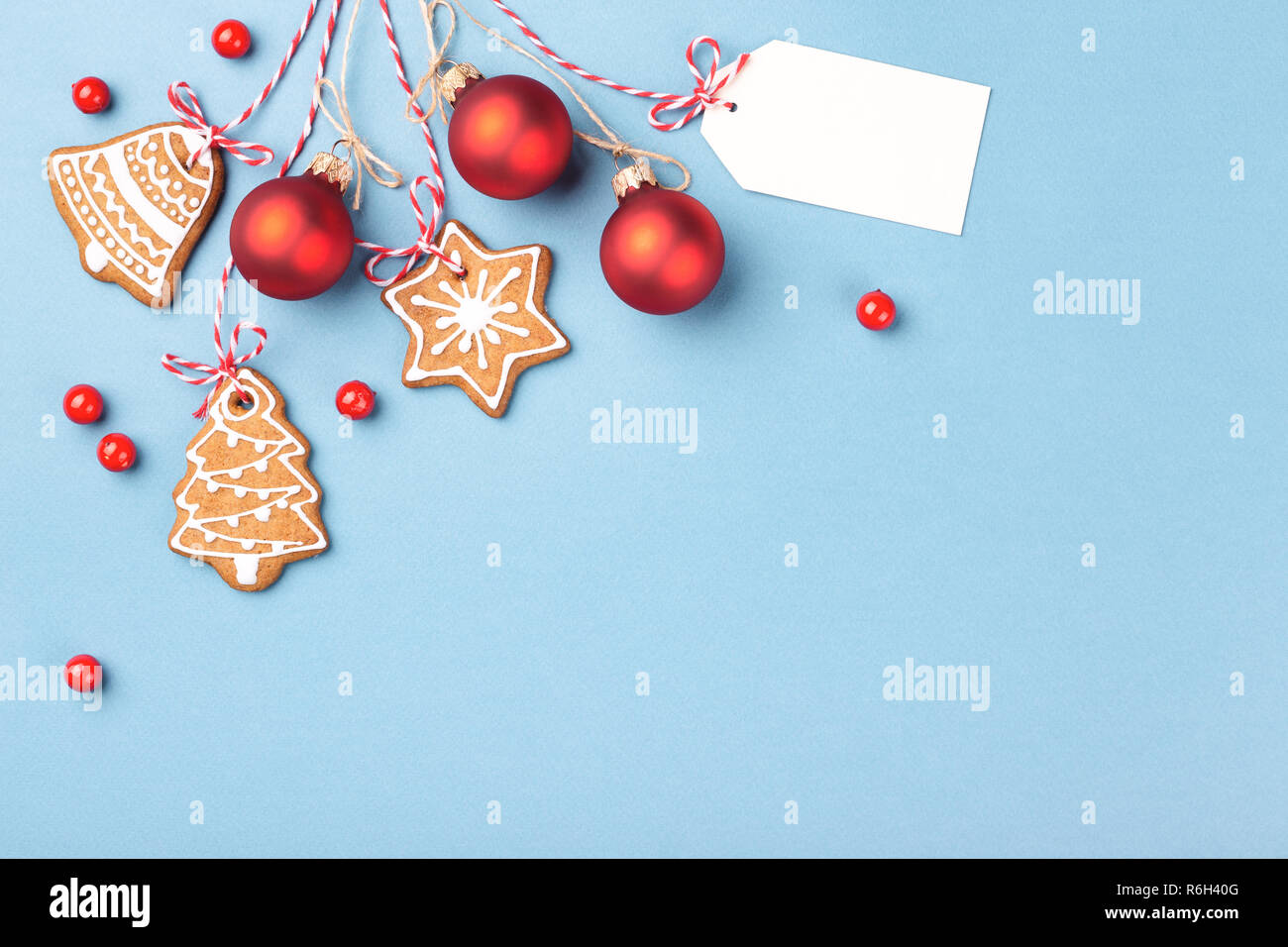 Gingerbread cookies con rosso palle di Natale e tag appeso su sfondo blu e decorata con frutti di bosco. Vista superiore, copia dello spazio. Foto Stock