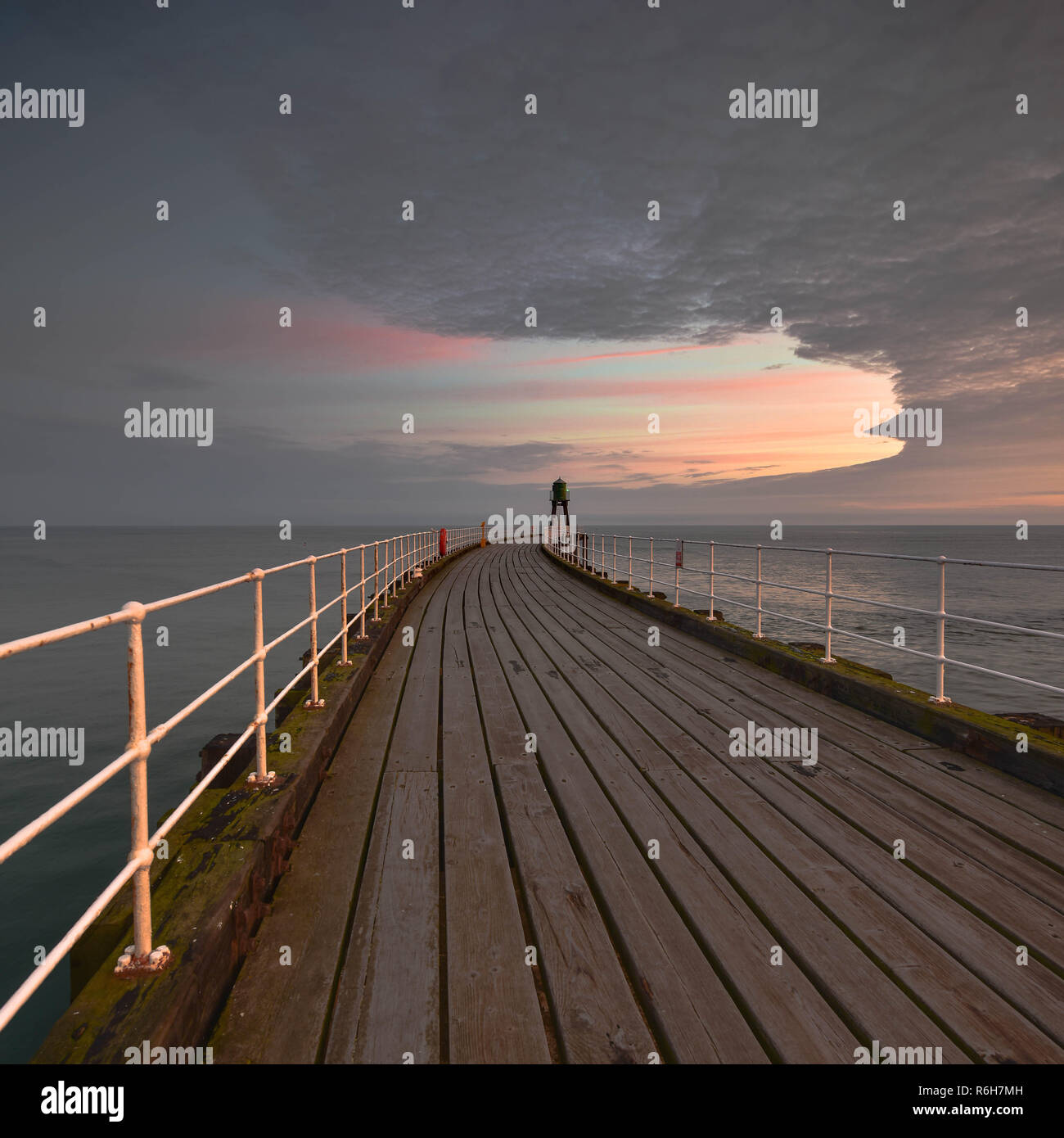Whitby pier e i momenti prima del sorgere del sole. Mi è stata stilata la relazione tra il molo e le nuvole. Come alcuni grandi Ying e Yang Foto Stock