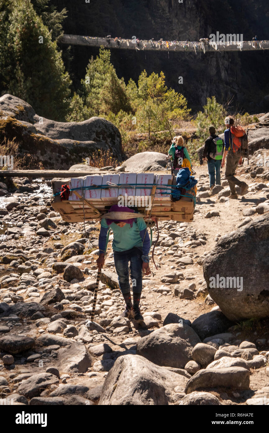 Il Nepal, Jorsale (Thumbug), porter portano carichi pesanti a Namche Bazar lungo il percorso accanto Dudh Khosi river Foto Stock