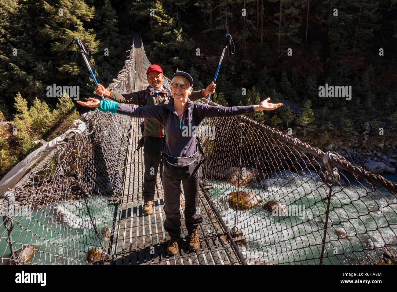 Il Nepal, Jorsale (Thumbug), senior trekker celebrando attraversando ponte di sospensione a Larja Dobham Foto Stock
