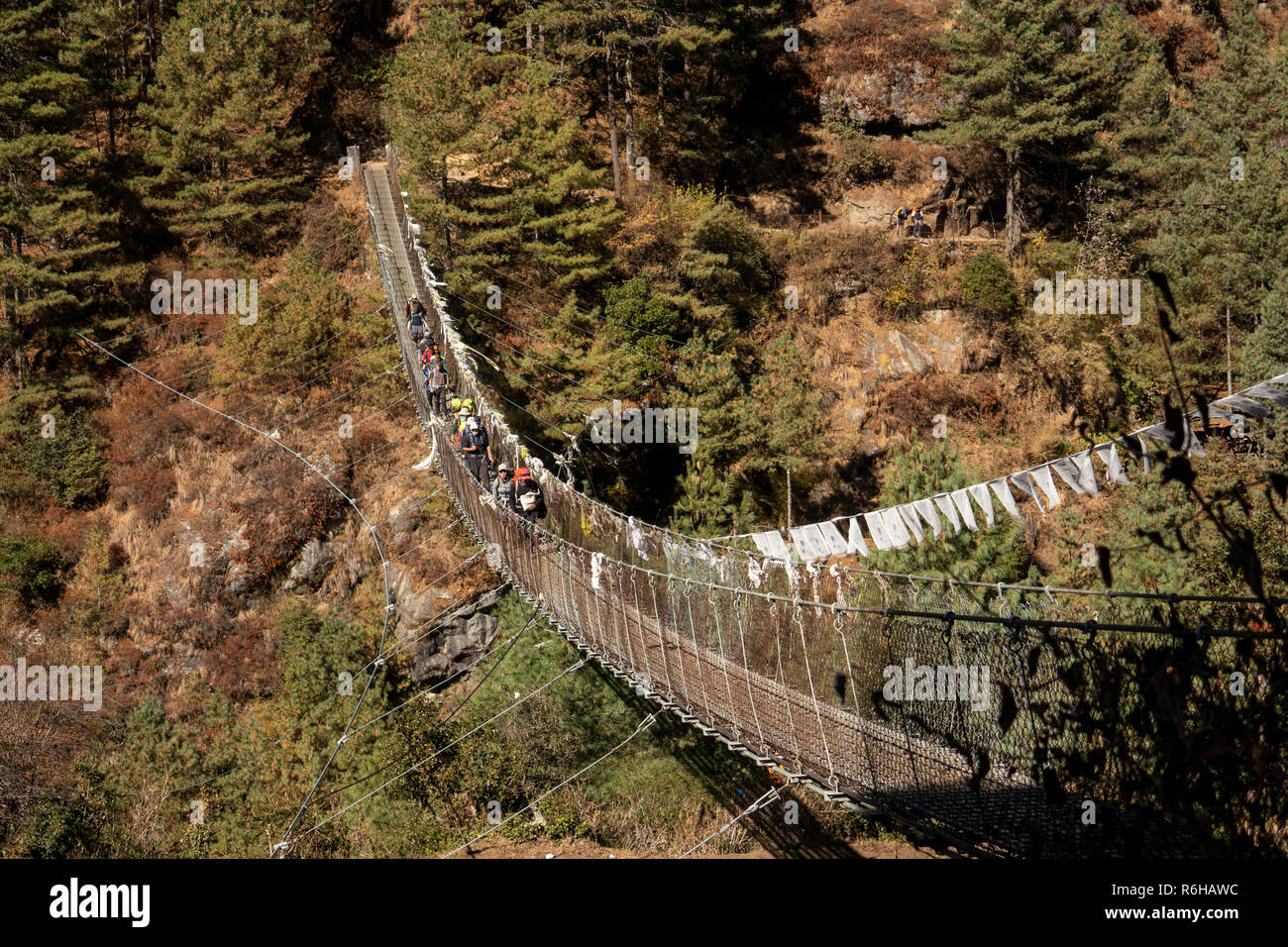 Il Nepal, Jorsale (Thumbug), linea di trekkers occidentale attraversando la sospensione in metallo ponte sul Dudh Khosi river Foto Stock