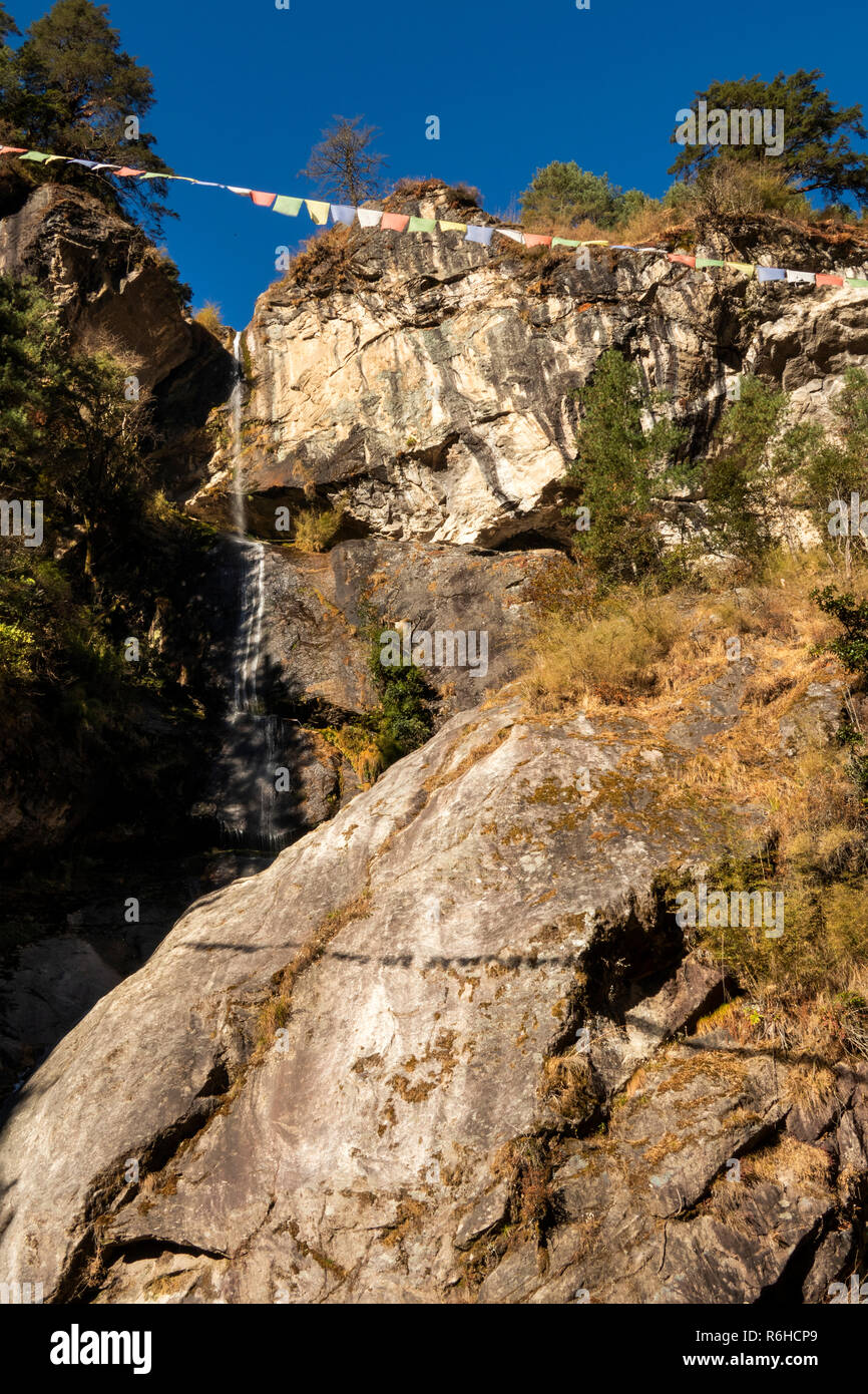 Il Nepal, Phakding, la preghiera buddista bandiere sopra la cascata alimentare Dudh Kosi River Foto Stock