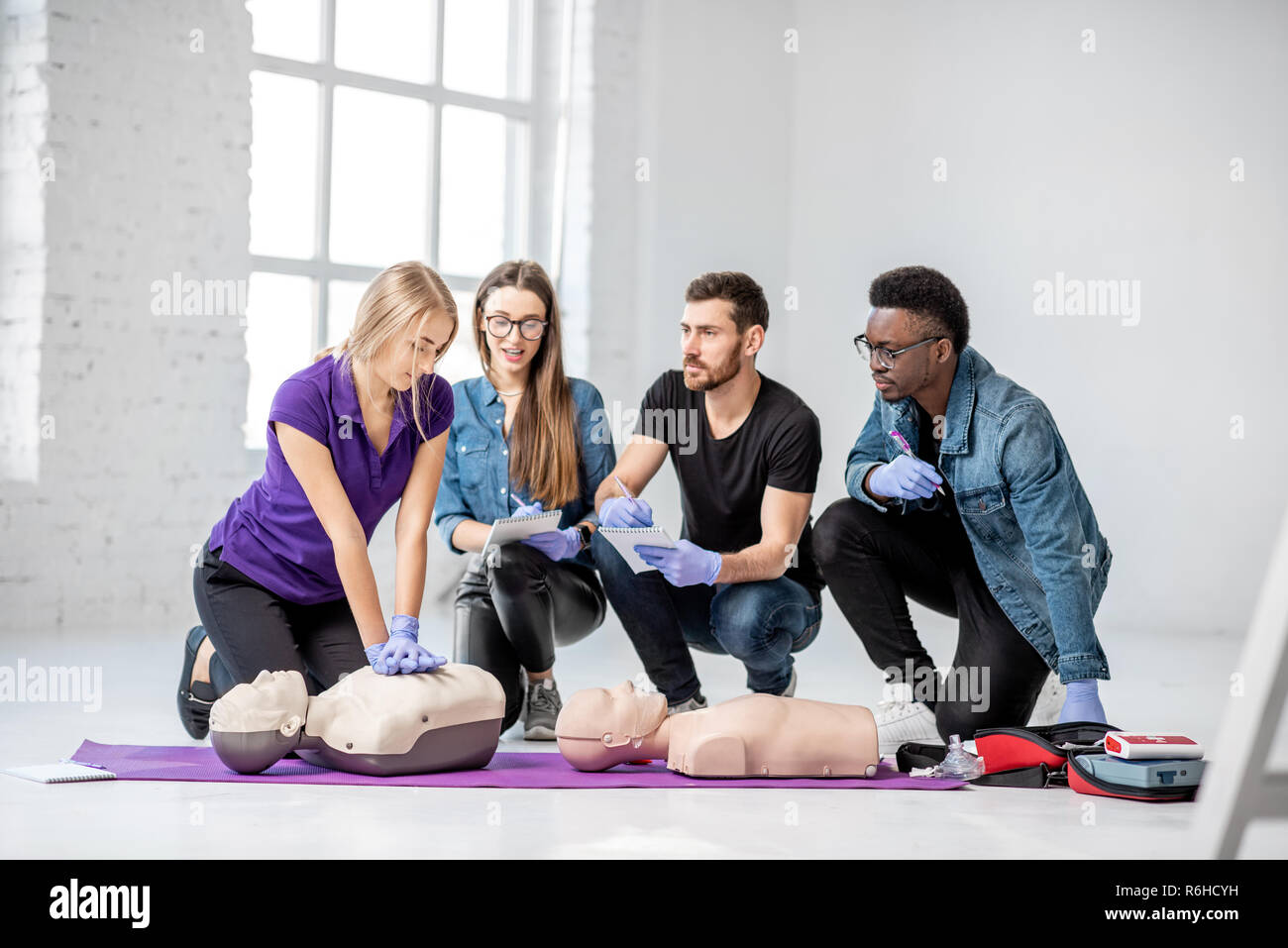 Un gruppo di giovani di imparare a fare la respirazione artificiale con manichini medici durante la formazione di primo soccorso in camera bianca Foto Stock