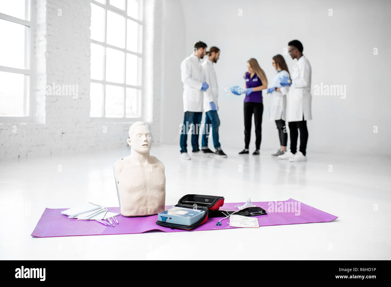 Primo soccorso materiale medico e manichini con un gruppo di giovani medici in piedi durante la pausa sullo sfondo Foto Stock