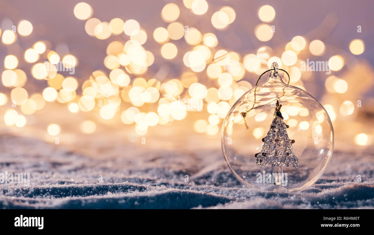 Natale sfera di vetro con albero in esso su sfondo d'inverno. La neve e le luci di Natale. Foto Stock