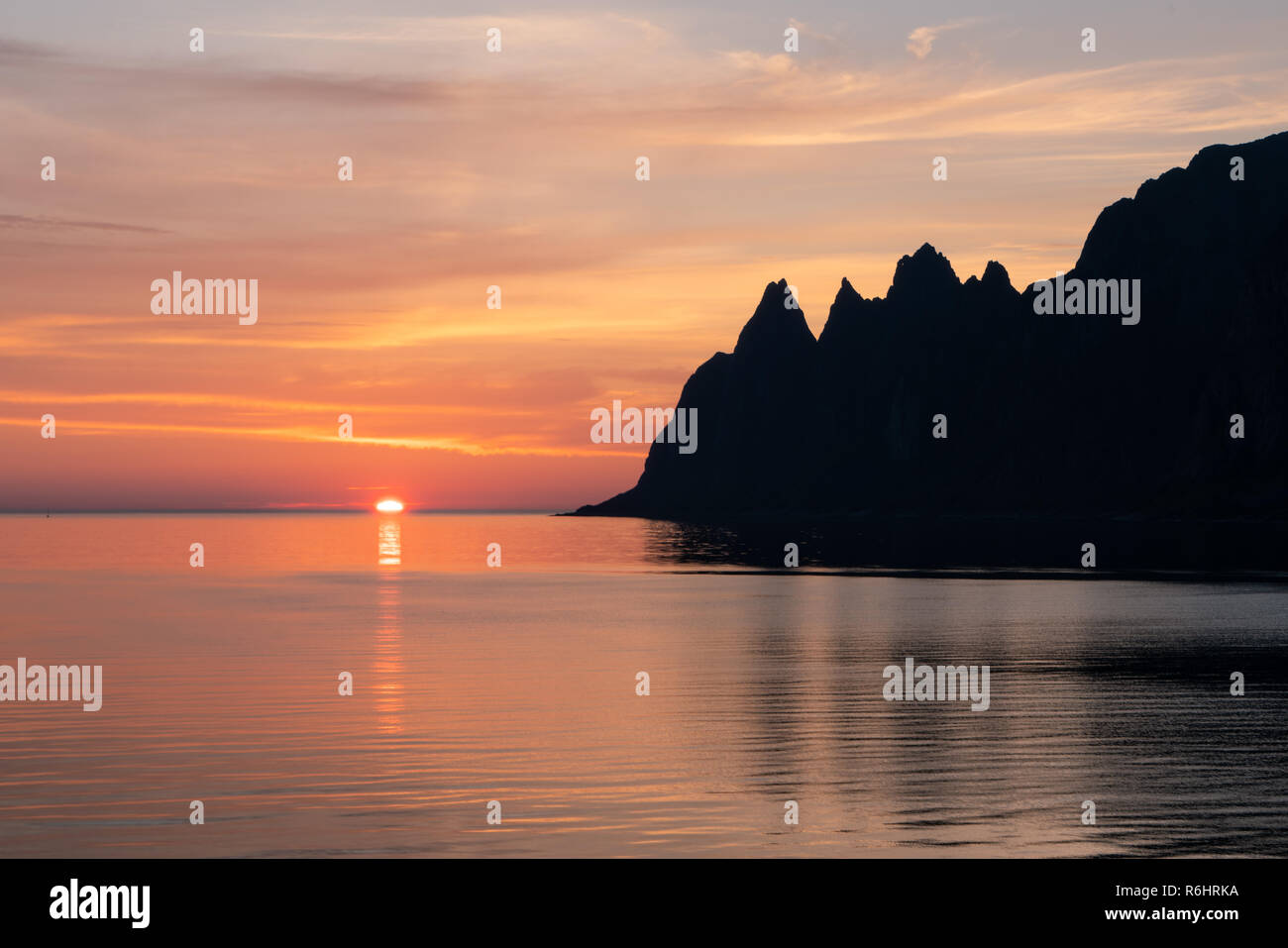 Golden Sunset dietro un oceano con silhouette di montagne Foto Stock