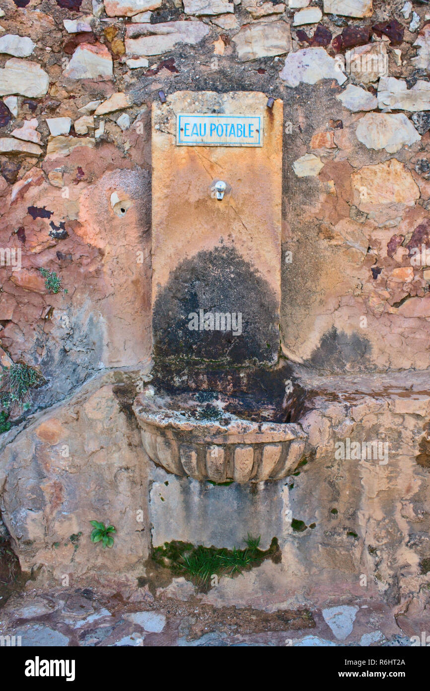 Vecchio acqua potabile fontana nel sud della Francia con un cartello blu che dice "rinking acqua" in francese. Foto Stock