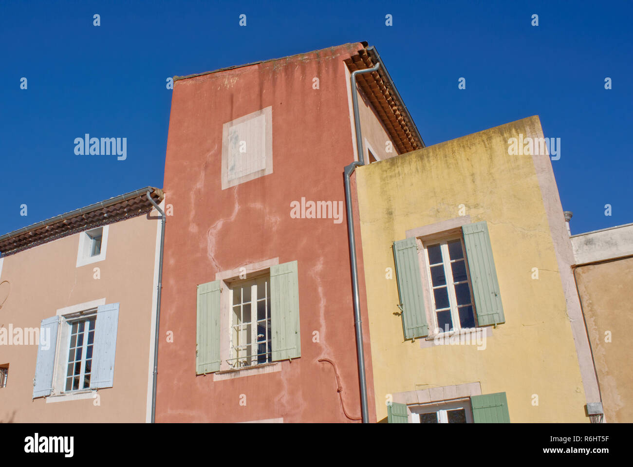 Case colorate in Roussilion nel Luberon, Francia meridionale. Cielo blu, rosso, giallo e arancione case. cornici bianche e persiane verdi. Foto Stock