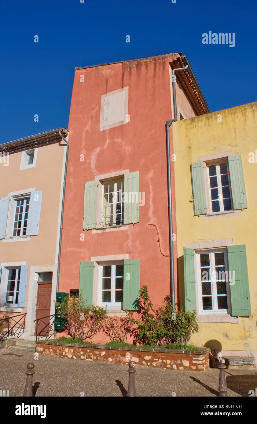 Case colorate in Roussilion nel Luberon, Francia meridionale. Cielo blu, rosso, giallo e arancione case. cornici bianche e persiane verdi. Foto Stock