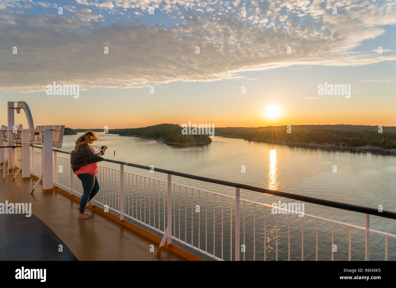 Giovane donna di scattare una foto dal ponte di Turku a Stockholm traghetto al tramonto, arcipelago di Turku, Finlandia Foto Stock