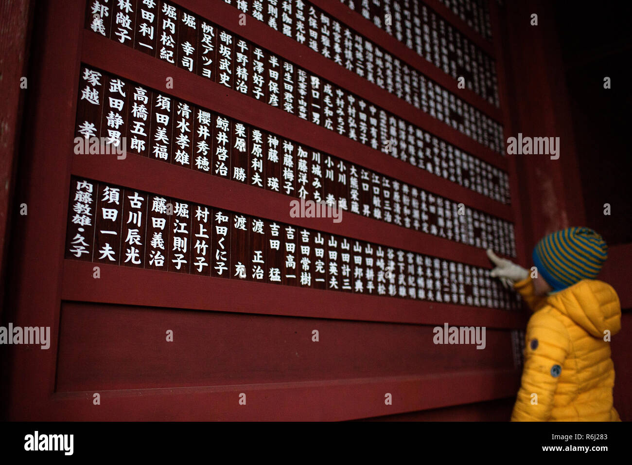 Western boy che puntano a script sulla parete di ingresso al santuario Okusha in Togakushi, Honshu, Giappone Foto Stock