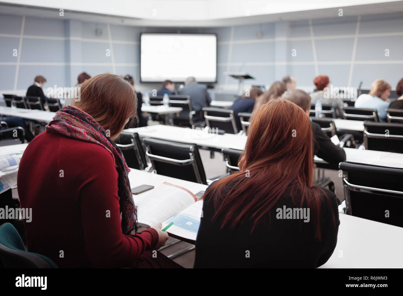 Donna di affari e gruppi di persone o agli studenti di ascoltare o guardare la rivista, libro di testo o opuscoli pubblicitari di сonference Presentazione o lezione. Orizzonte Foto Stock
