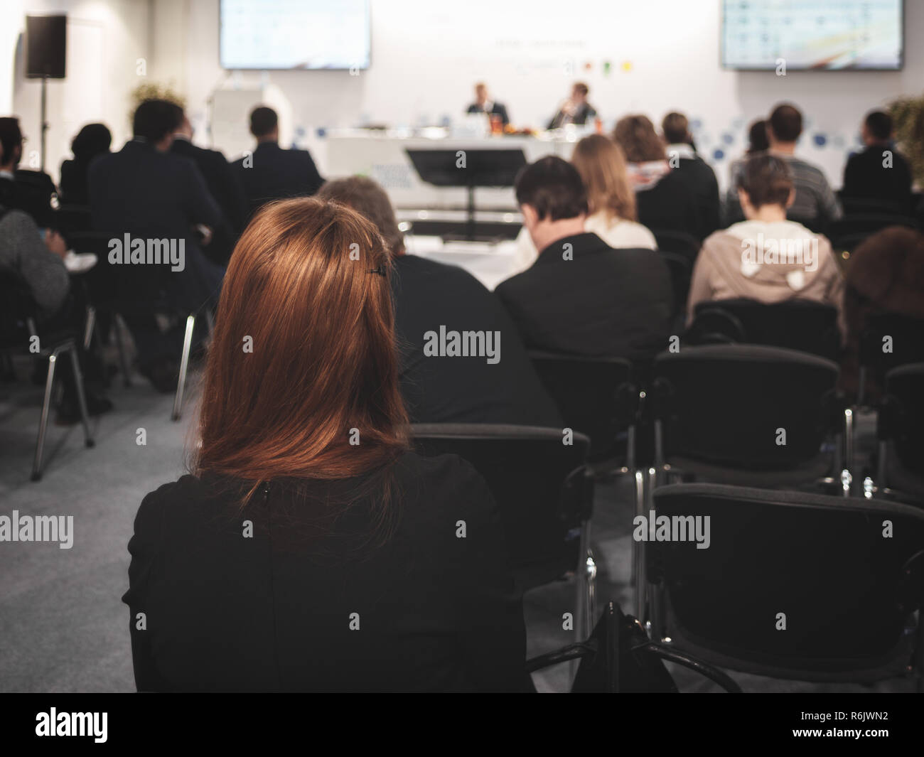 Business donna con i capelli lunghi e le persone in ascolto sulla Conferenza o sulla formazione nella hall Foto Stock