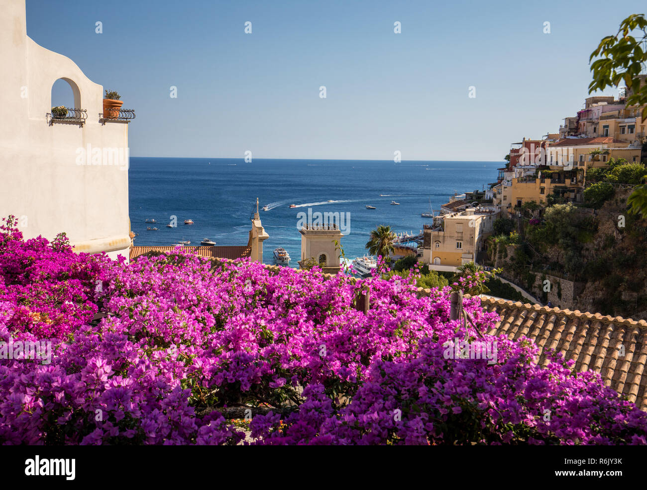 Positano incorniciato da rosa bouganville e barche in background. Colorato Positano, la perla della Costiera Amalfitana, con le sue variopinte case e immobili arroccato su una collina che si affaccia sul mare. Italia Foto Stock