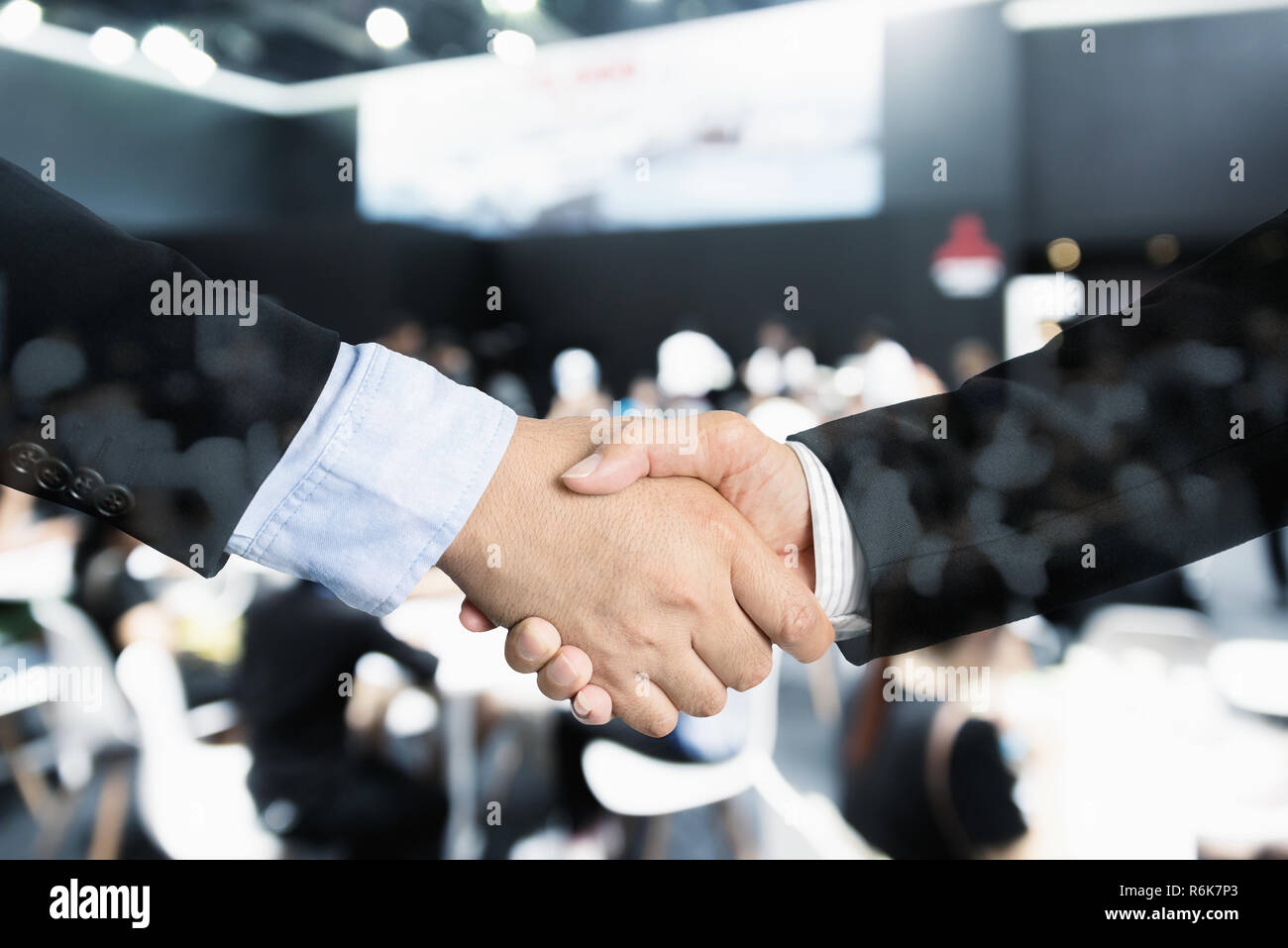 Trattativa o accordo concetto business handshake, doppia esposizione, cooperazione o partenariato imprese con seminario incontro di conferenza in background. Foto Stock