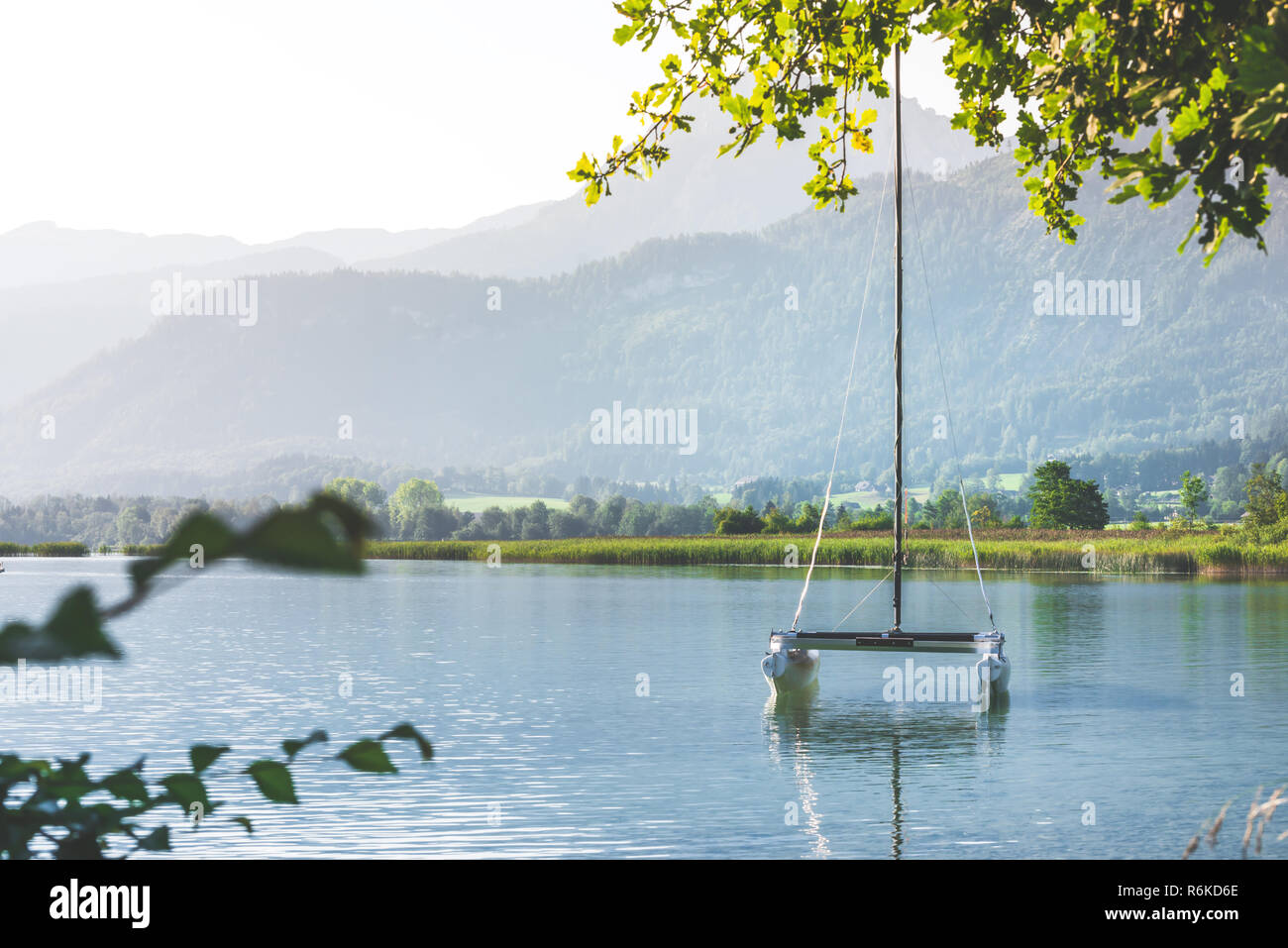 Piccolo yacht presso il lago di montagna nelle Alpi in mattinata Foto Stock