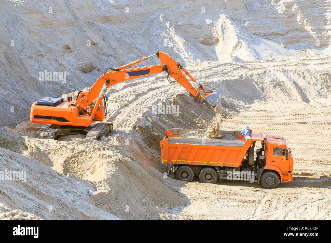 Il lavoro dell'escavatore e del carrello in corrispondenza di una cava di sabbia. Escavatore di sabbia di caricamento in un autocarro con cassone ribaltabile. Foto Stock