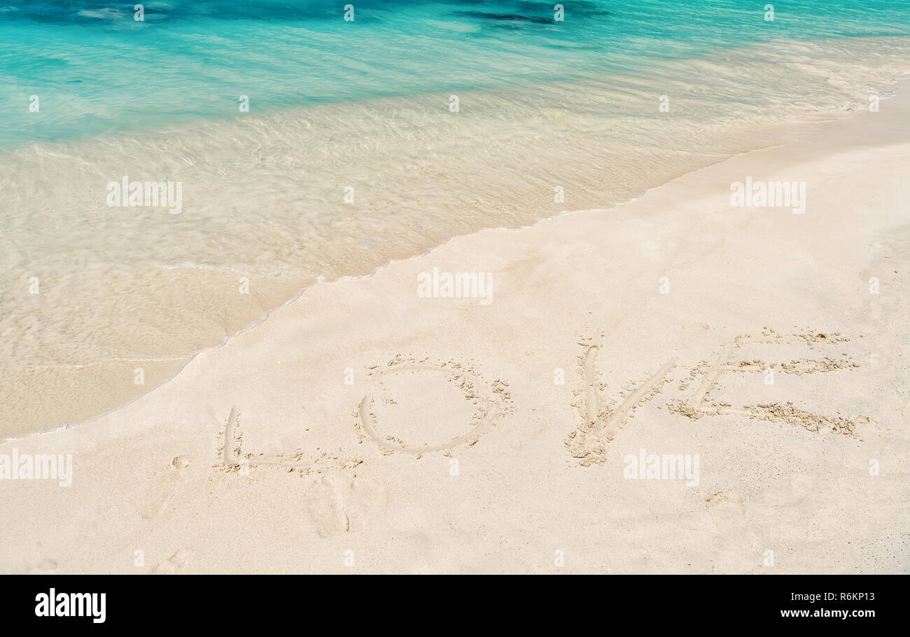 Amore la parola scritta sulla sabbia bianca in st Johns, Antigua. Mare o oceano spiaggia con acque turchesi onde sulla giornata di sole. La vacanza estiva, vacanze sulla celebrazione dei caraibi. Il giorno di San Valentino concetto Foto Stock