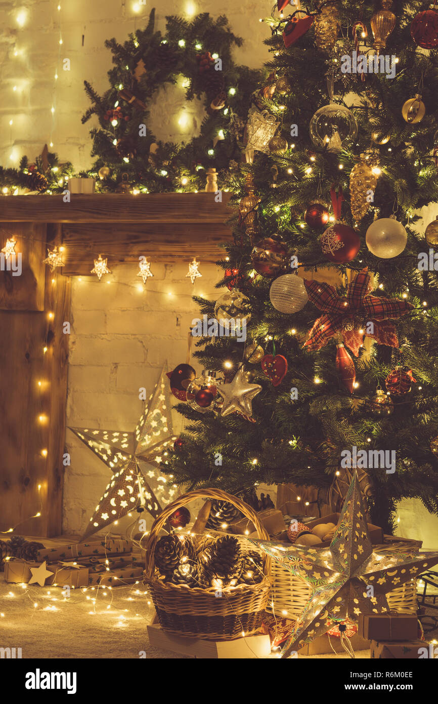 Bellissimi interni accoglienti, camino decorato con legno massello mantelpiece, illuminato di albero di Natale con baubles e ornamenti, stelle e le luci delle candele. Foto Stock