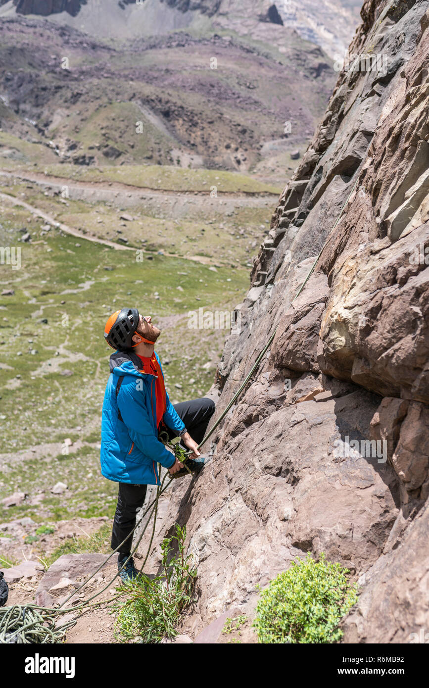 Uno scalatore uomo lavora con la corda dopo la messa il percorso è salito in ordine di discesa a corda doppia alla base della parete di arrampicata all'interno di Andes Foto Stock