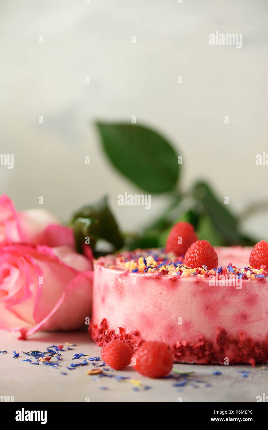 Le rose rosa e lampone torta con frutti di bosco freschi, rosmarino, fiori secchi su sfondo di calcestruzzo. Copia dello spazio per il tuo testo. Festa di compleanno del concetto. Foto Stock