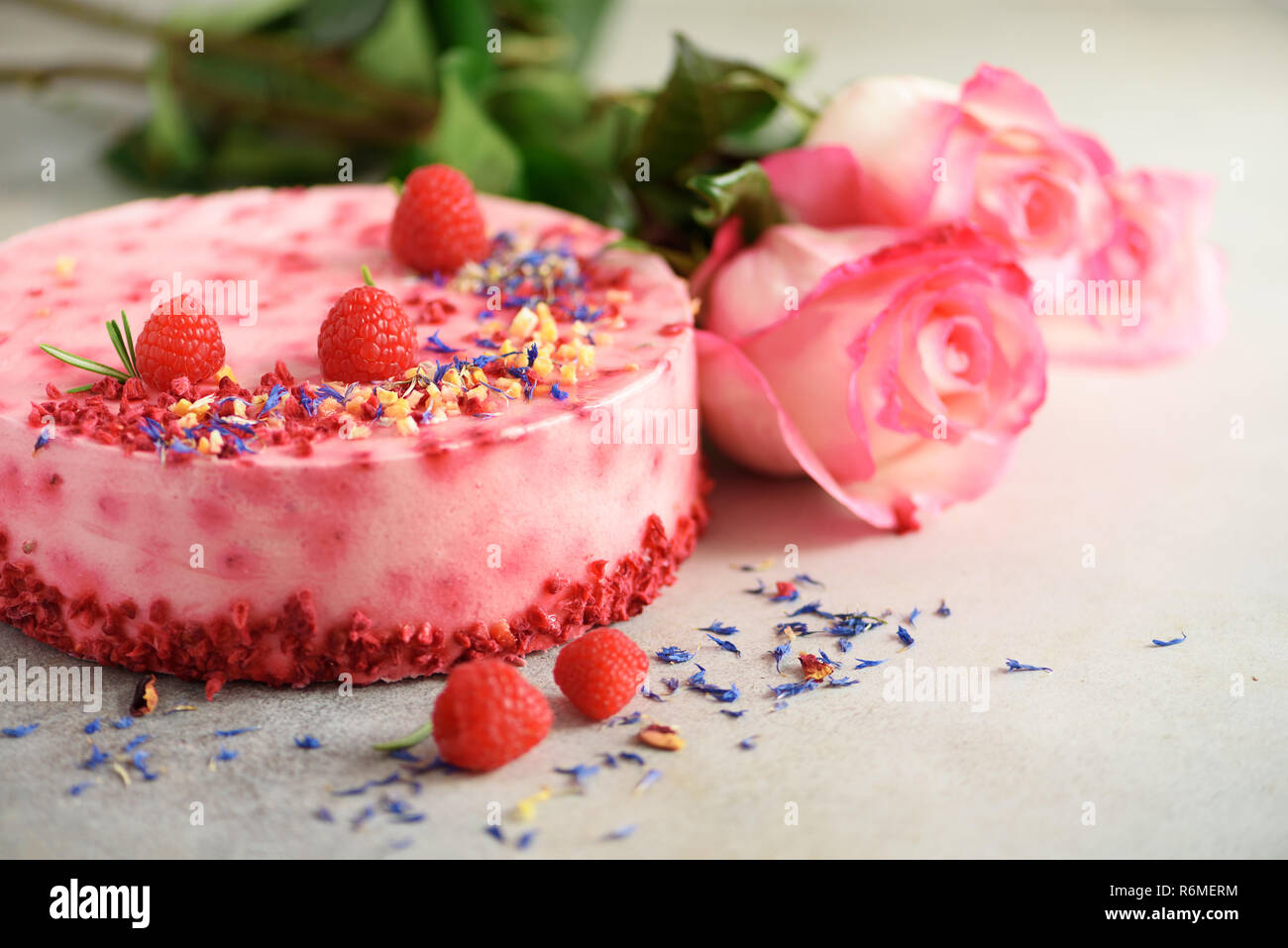 Le rose rosa e lampone torta con frutti di bosco freschi, rosmarino, fiori  secchi su sfondo di calcestruzzo. Copia dello spazio per il tuo testo.  Festa di compleanno del concetto Foto stock -