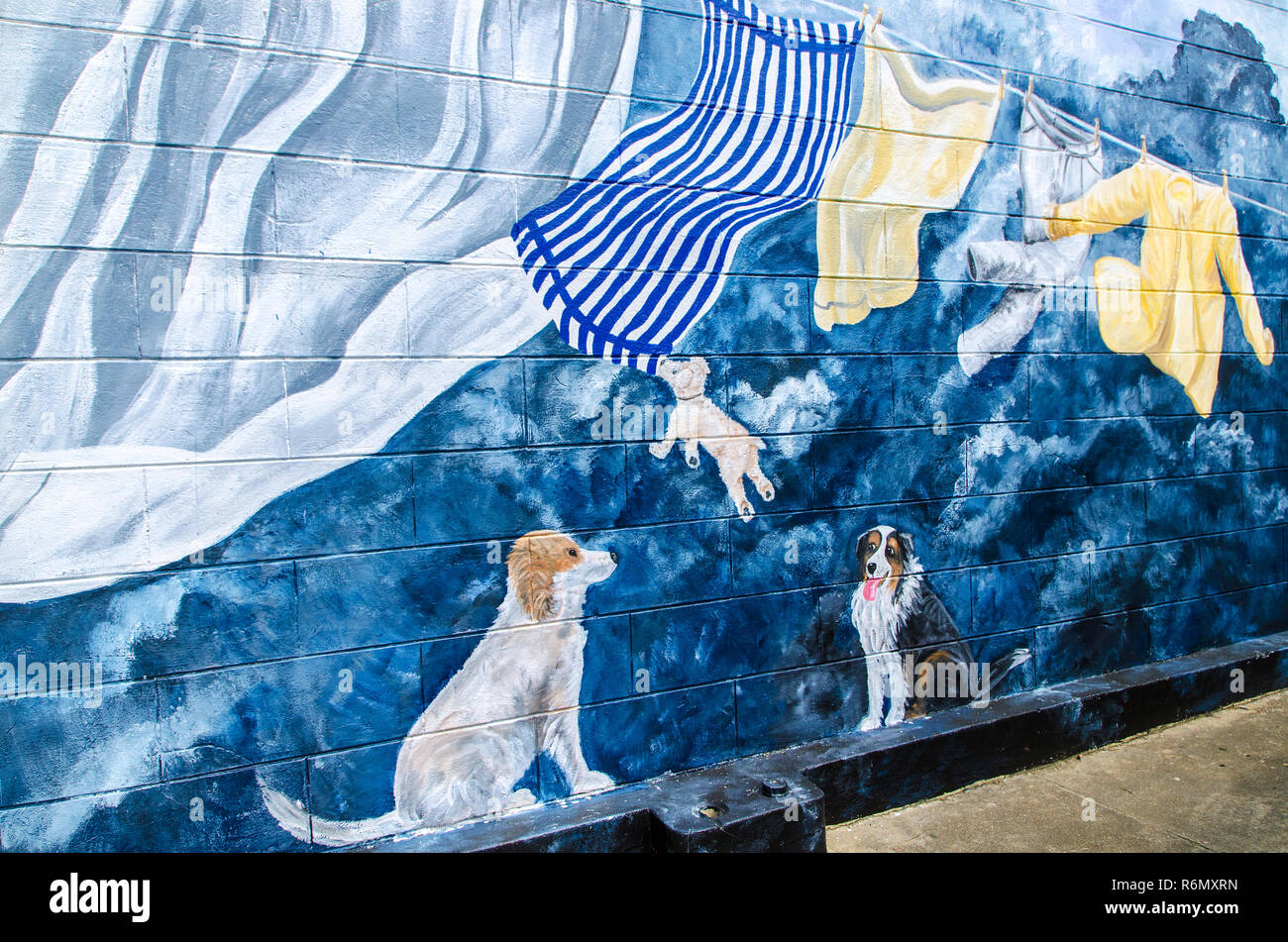 Tre cani giocare con servizio lavanderia appesi da uno stendibiancheria in questa carta murale sul lato di lavanderie a secco negozio nel centro di West Point, Mississippi. Foto Stock