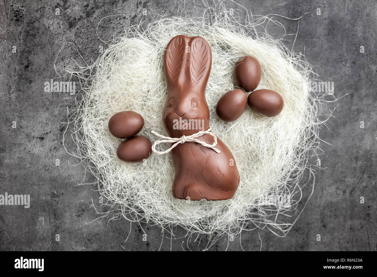 Il cioccolato coniglietto di Pasqua e le uova in un nido su sfondo rustico Foto Stock