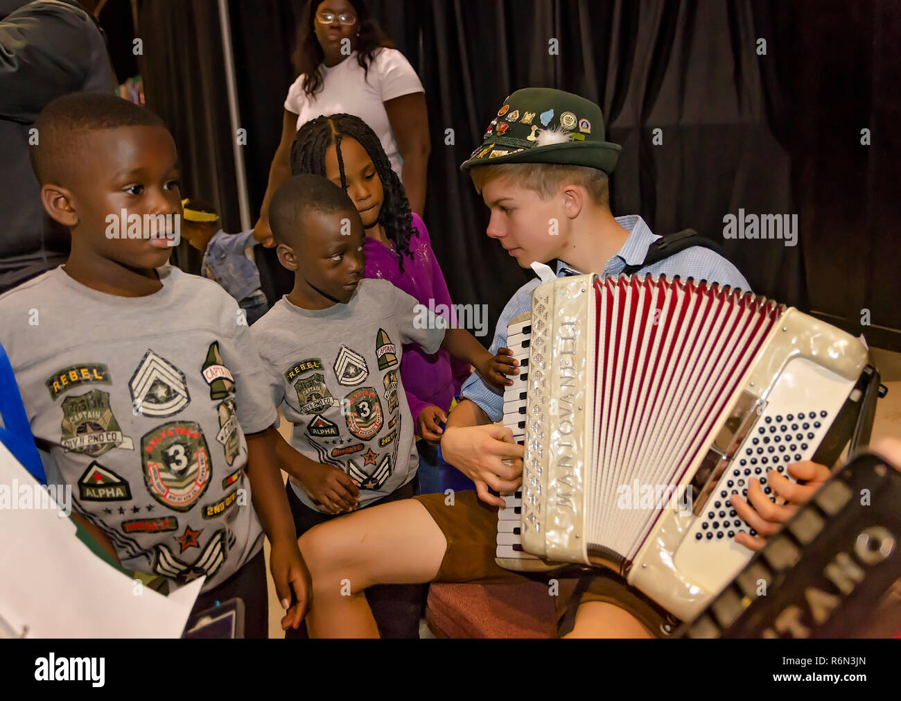 Un giovane musicista mostra la sua fisarmonica per bambini curiosi alla XXXIV Mobile annuale Festival Internazionale, nov. 17, 2018 in Mobile, Alabama. Foto Stock