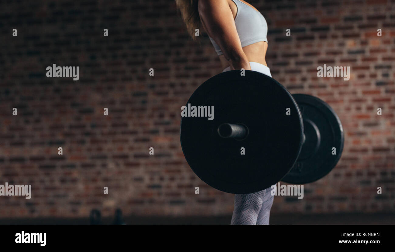 Donna esercizio con pesi pesanti nel fitness club. Focus sul peso pesante barbell sollevato da atleta femminile. Sezione mediana. Foto Stock