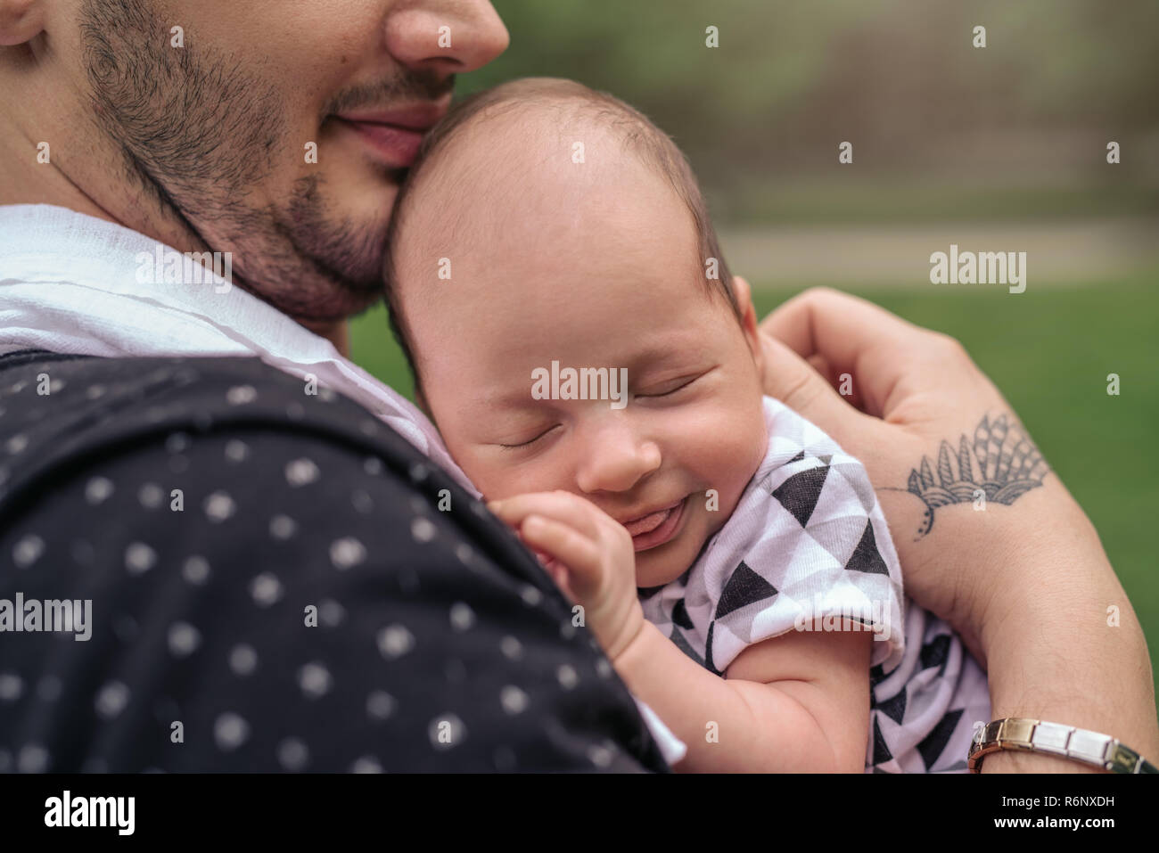 Padre sorridente cullano il suo bambino sul suo spallamento esterno Foto Stock