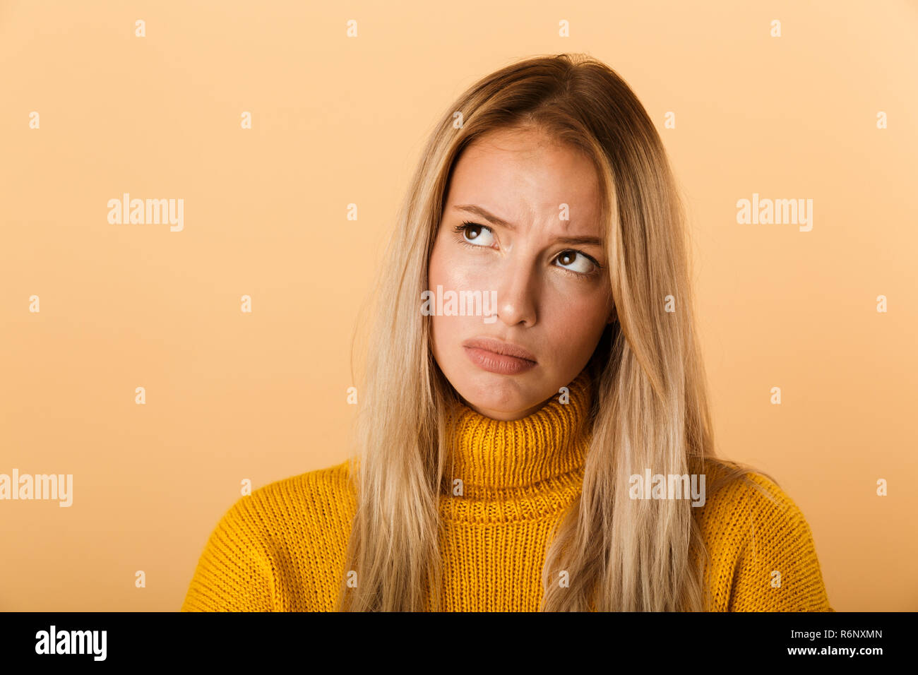 Close up ritratto di sconvolgere un giovane donna vestita di un maglione in piedi isolato su sfondo giallo Foto Stock