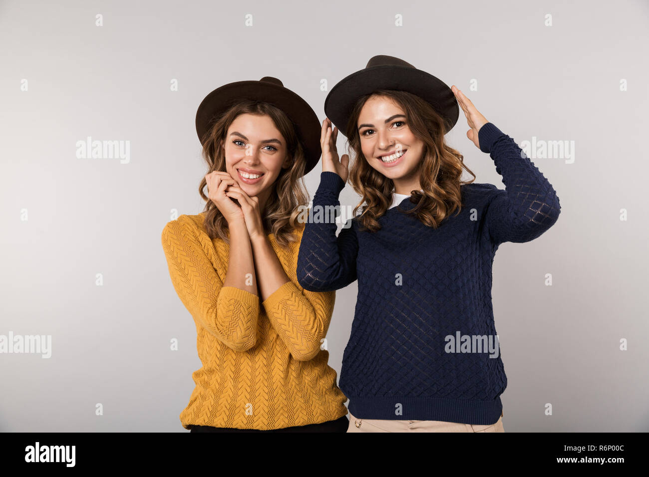 Immagine delle due donne allegro indossare cappelli sorridente in telecamera isolate su uno sfondo grigio Foto Stock